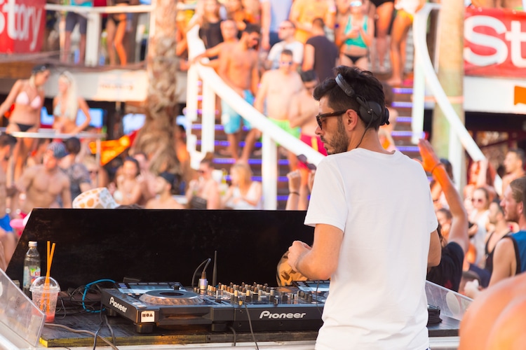 A crowd of people party on Pag Island in Croatia while a DJ plays music