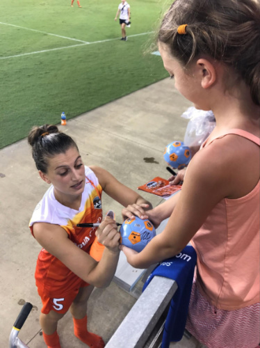 A Dash Player signing the ball of a young girl