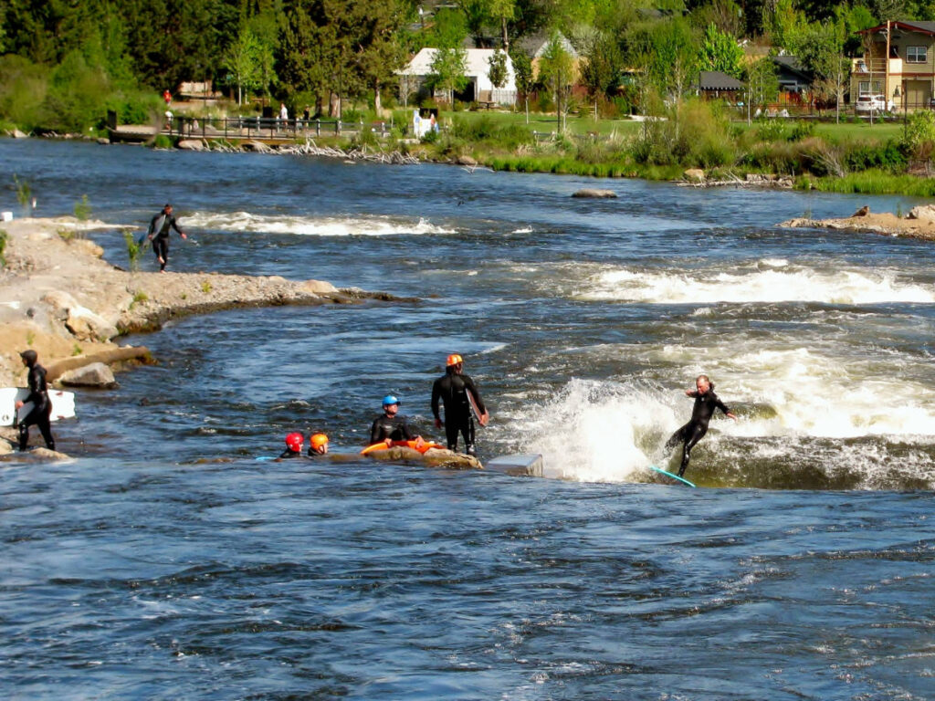 Group of people river surfing in the whitewater park at Deschutes River