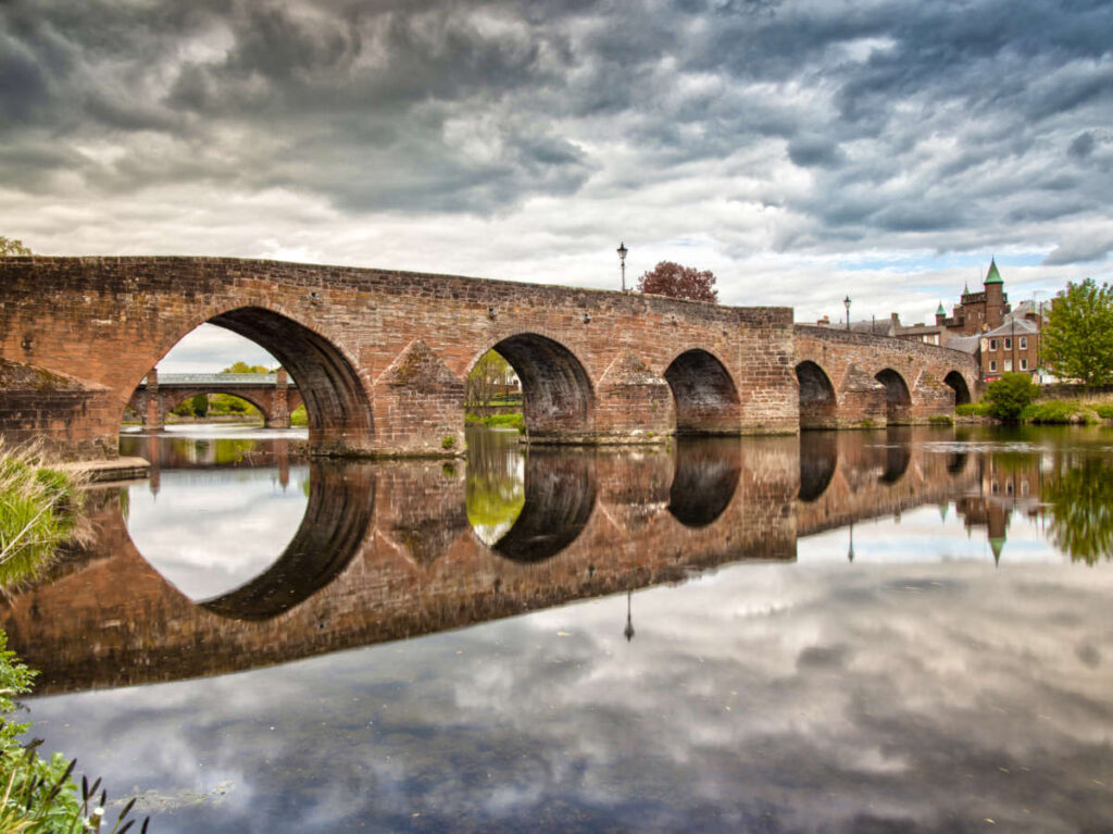 The Devorgilla Bridge reflecting on the water on a gloomy day