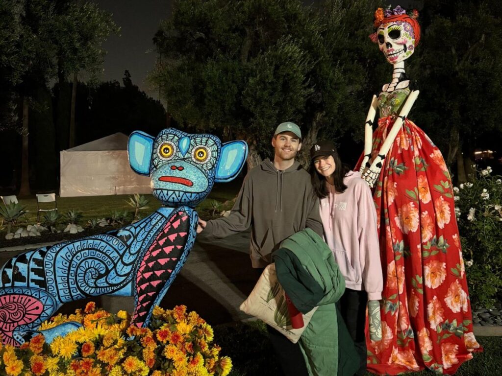 Author Betty and Michael taking a picture with the Día de los Muertos statues at Hollywood Forever Cemetery