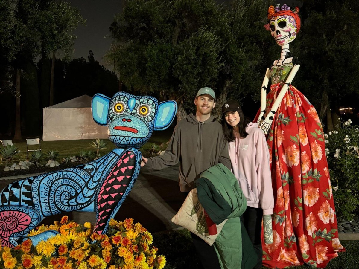 Author Betty and Michael taking a picture with the Día de los Muertos statues at Hollywood Forever Cemetery
