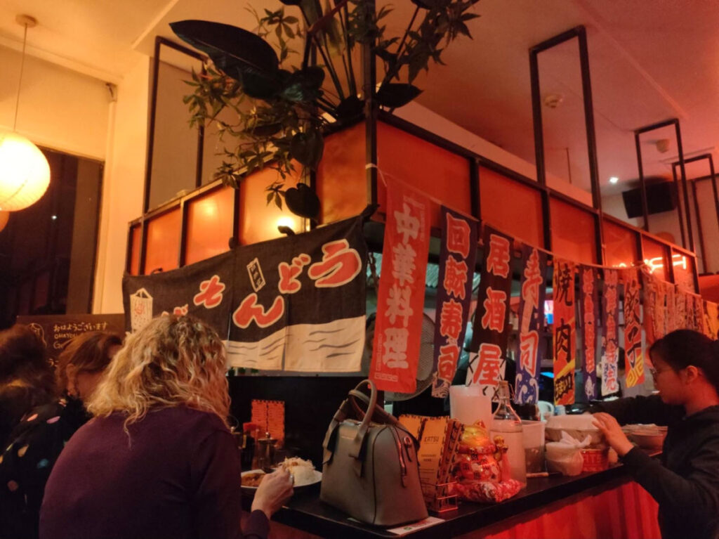 People dining on the ground floor in Katsu, peeking through to the kitchen