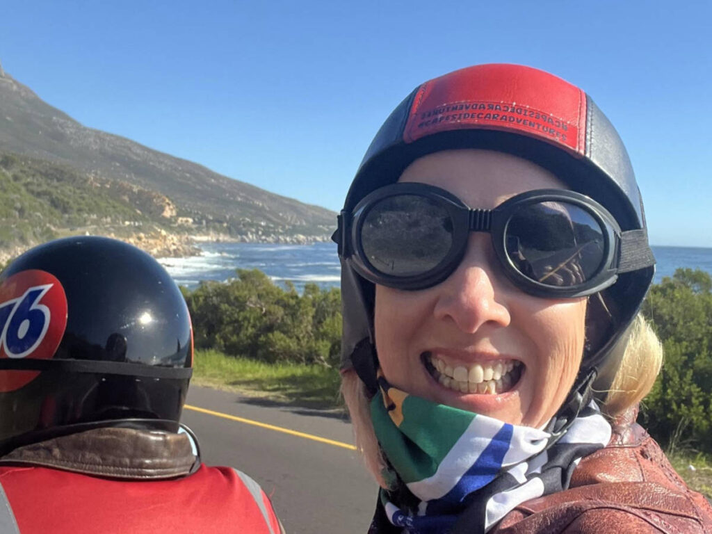 The author Elise Kirsten, riding on the back of a vintage motorcycle