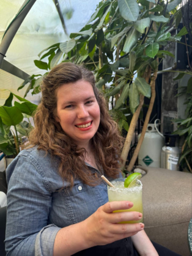 The author Elizabeth Demolat, holding a glass of cocktail drink at Greenhouse Bar