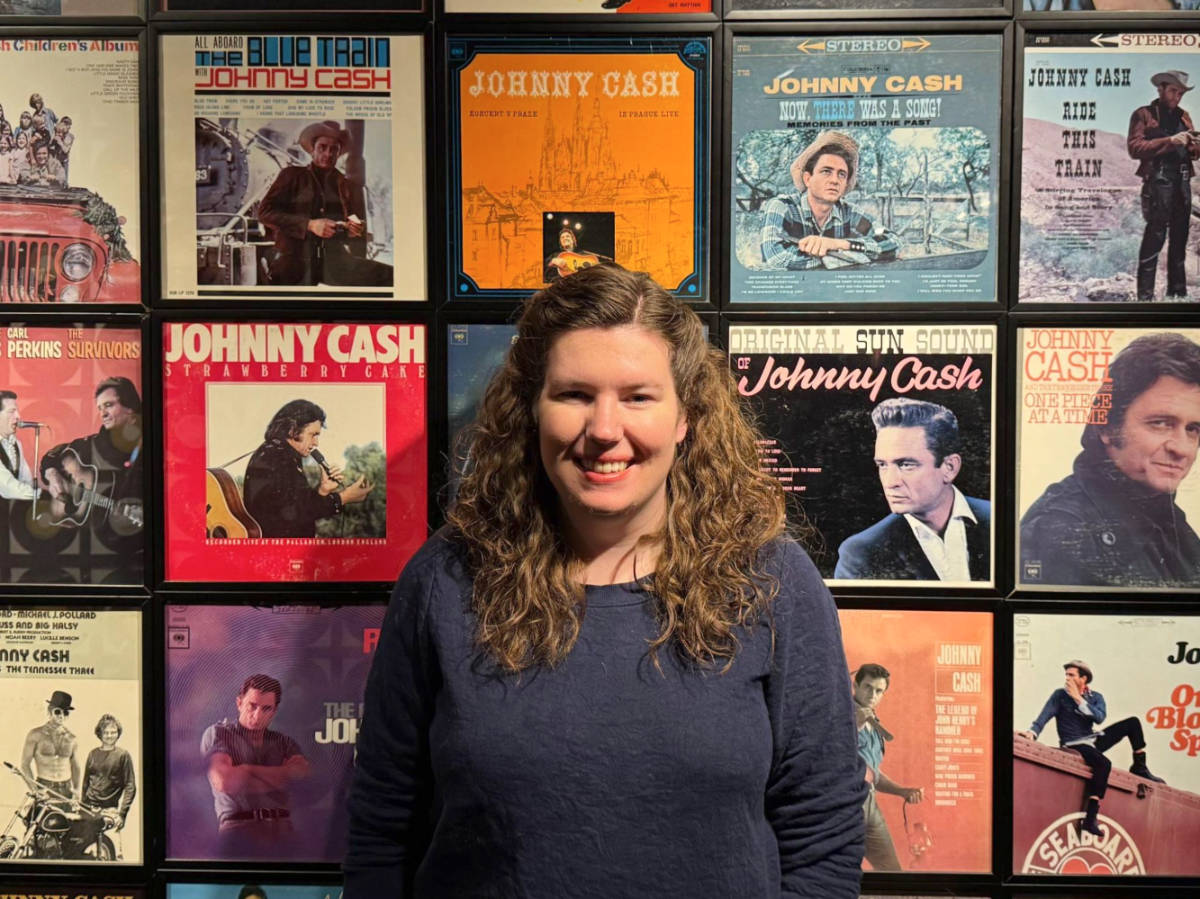 The author Elizabeth posing for a photo with the gallery wall inside the Johnny Cash Museum