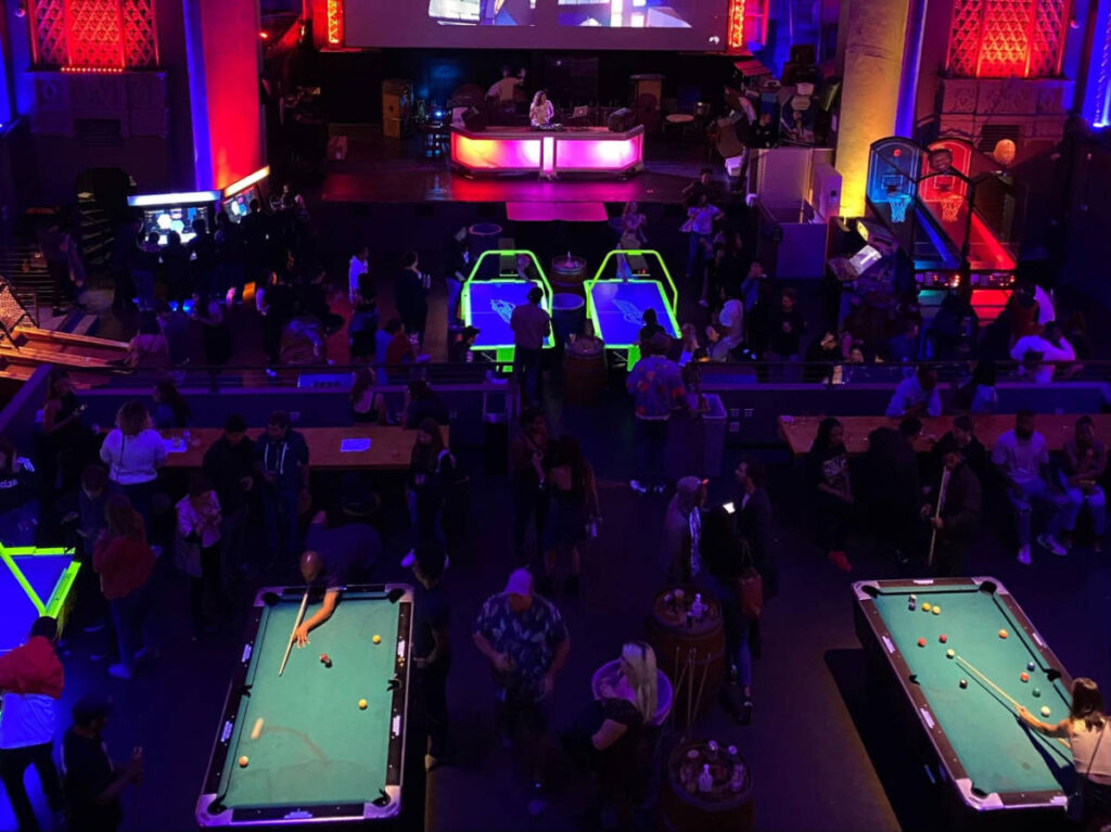 People playing different arcade games on the ground floor of Emporium