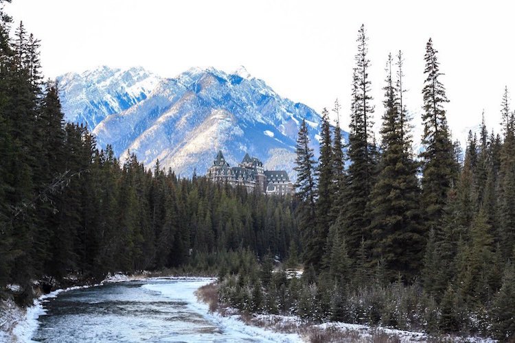 The Fairmont Hotel surrounded by a river, mountains, and trees in Banff National Park