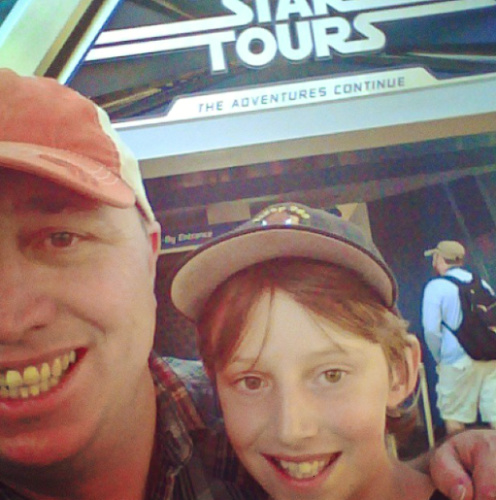 A father with her daughter, smiling for a photo at the Disneyland