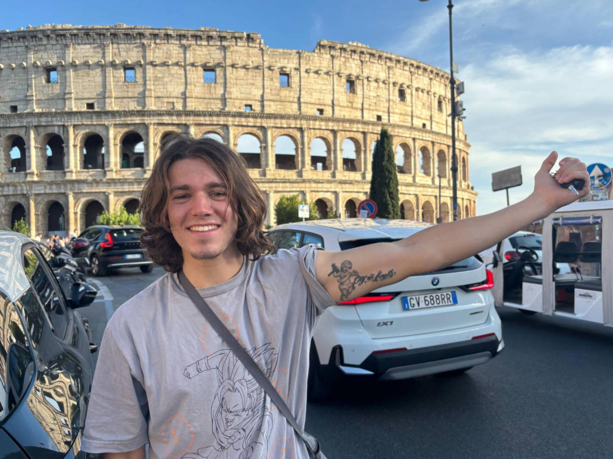 A man showing off his Los Angeles tattoo on his arm in front of the Colosseum