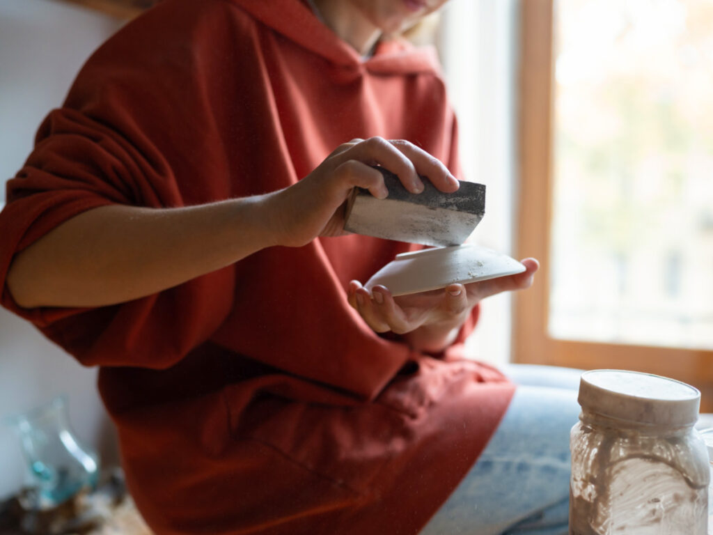 A woman at Firestick Pottery Studio holds a piece of pottery