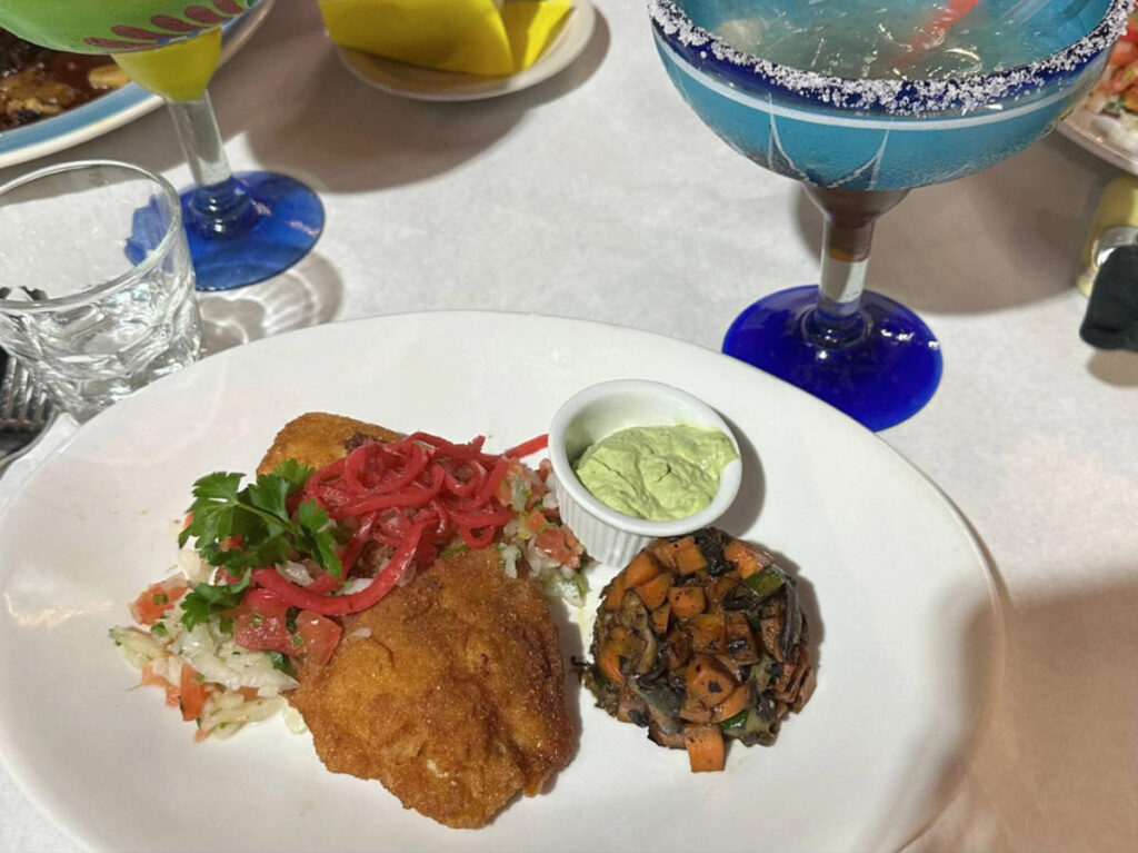A plate with fish special and a mango margarita on the side