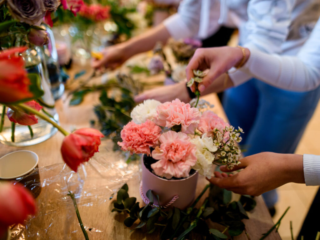 Two people arranging several beautiful bouquets of flowers