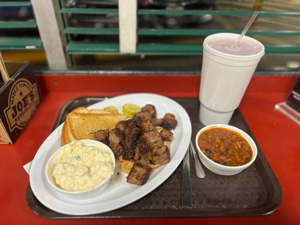 A plate with burnt ends with baked beans and potato salad at Joe’s BBQ
