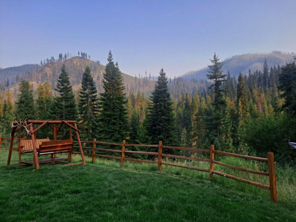 A wooden swing with Montana's forested hills in background