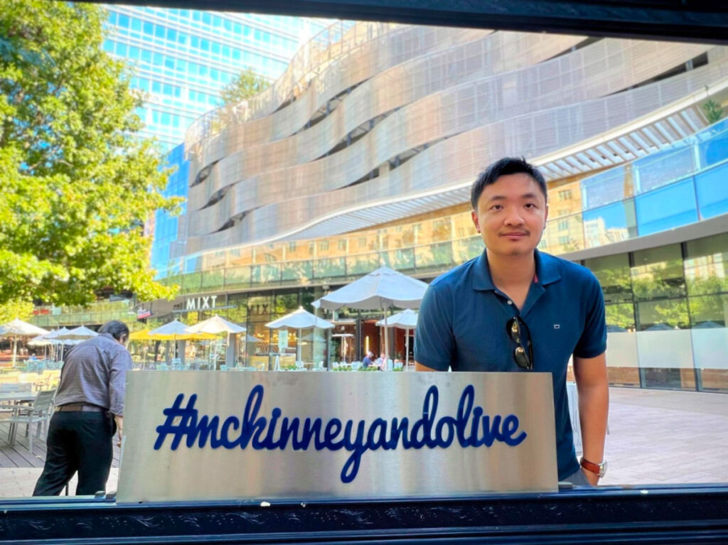 Sarah Heath's partner posing in front of McKinney & Olive, Dallas