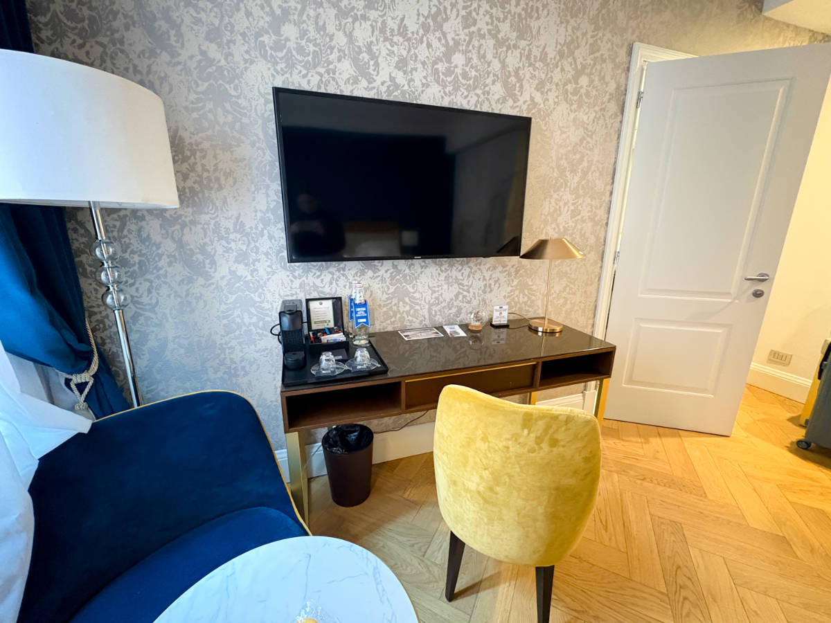 The TV on the wall above the desk area in the hotel room