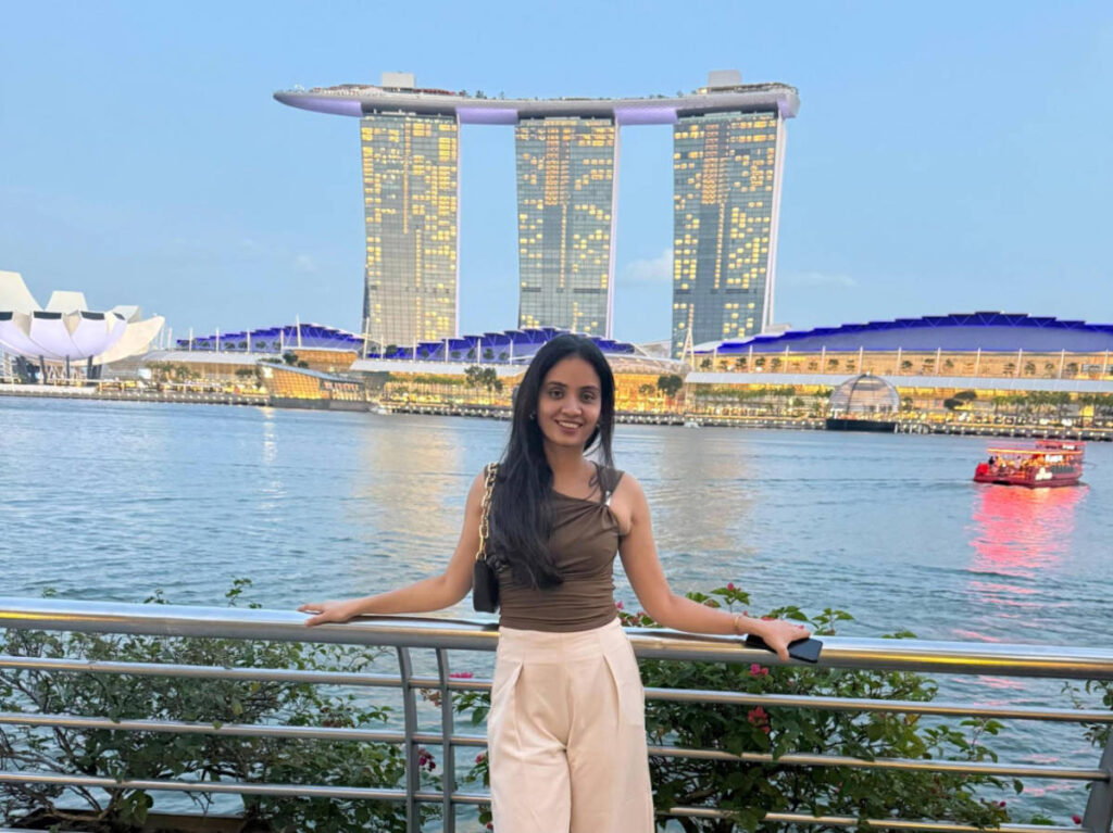 The author, Advaita smiling for a photo at the Fullerton Promenade with the Marina Bay Sands Hotel on her background