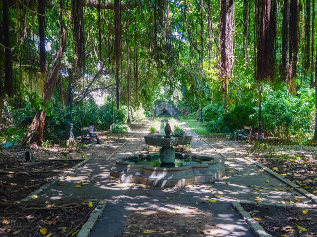 A woman sitting on the bench surrounded by lush greenery at the garden in Casa Blanca