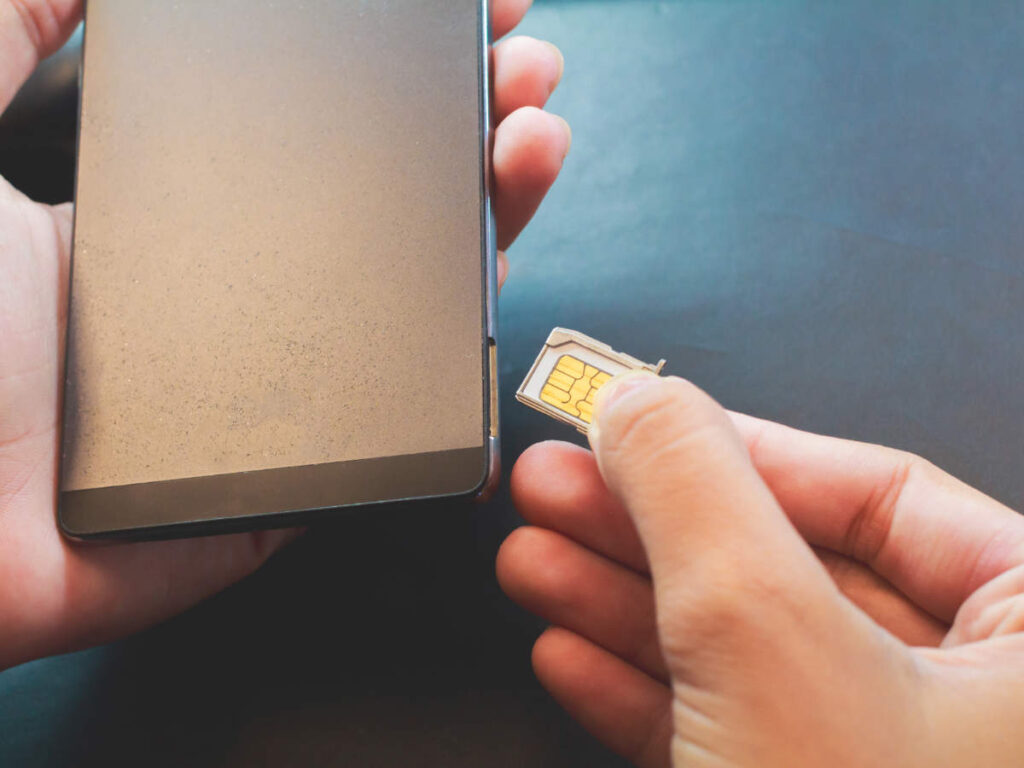 A hand inserting a Georgian SIM Card on a phone