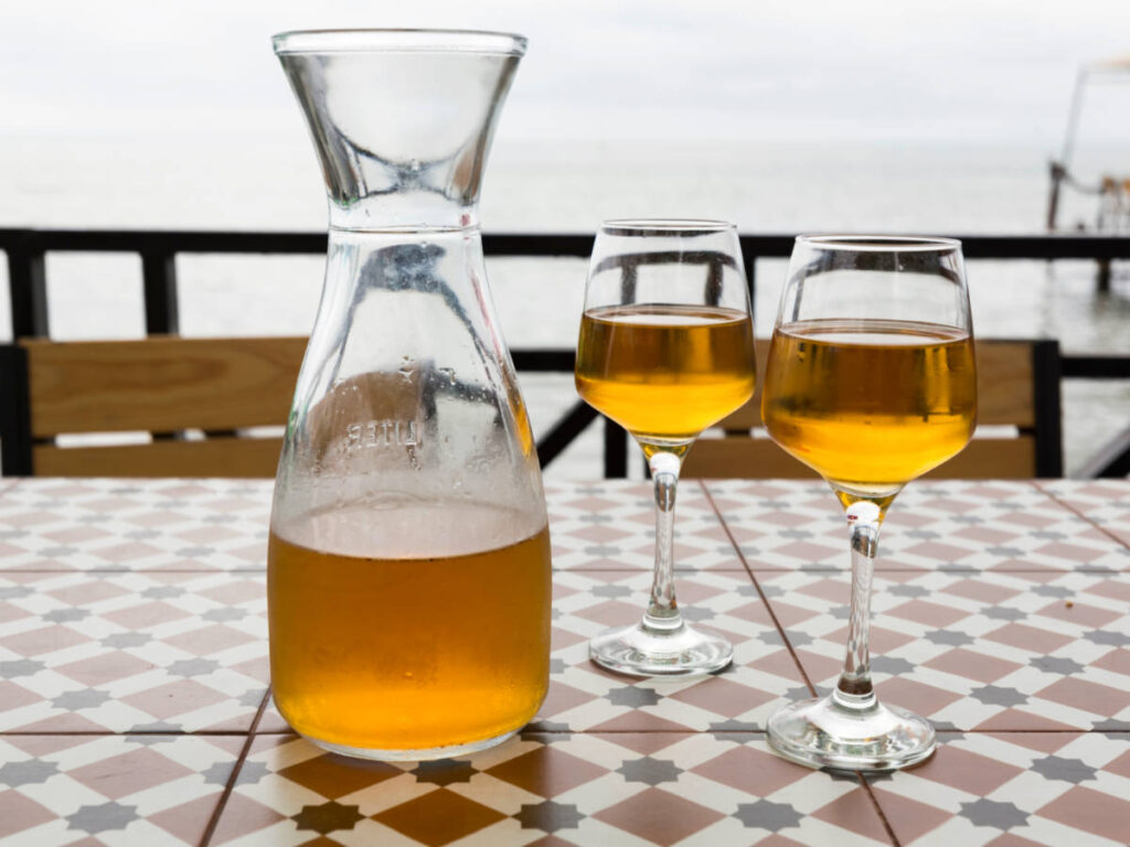 A pitcher with two glasses of golden colored wine in Georgia