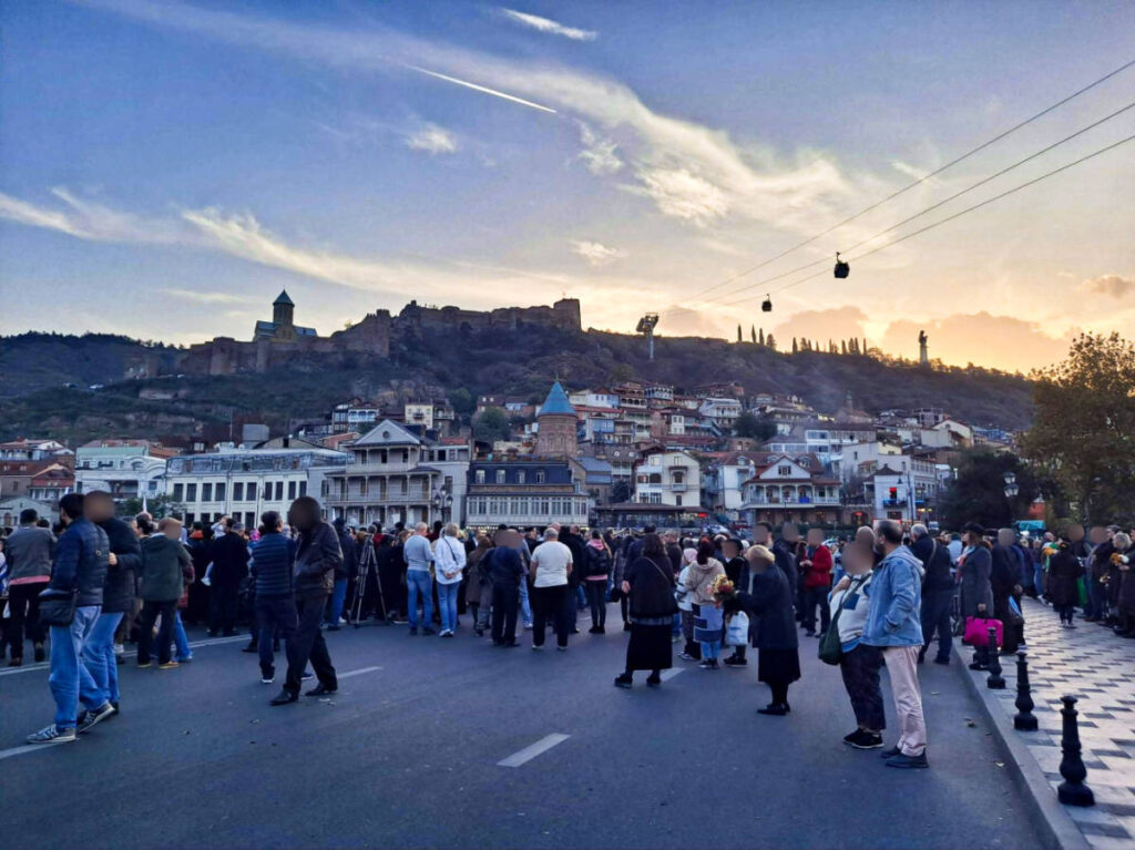 The Georgians wearing neutral colors gathering in the middle of the street at sunset