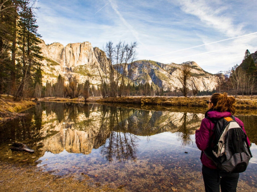 A female hiker admiring the picturesque view at of the mountains mirroring on the lake