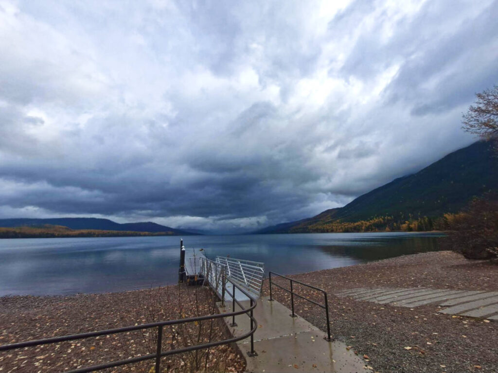 A boardwalk near the lake surrounded by mountain views in fall