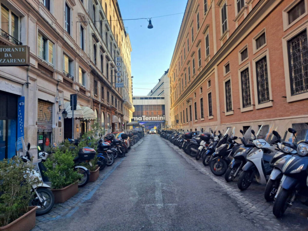 A street with parked motorcycles leading to Rome’s Termini Station