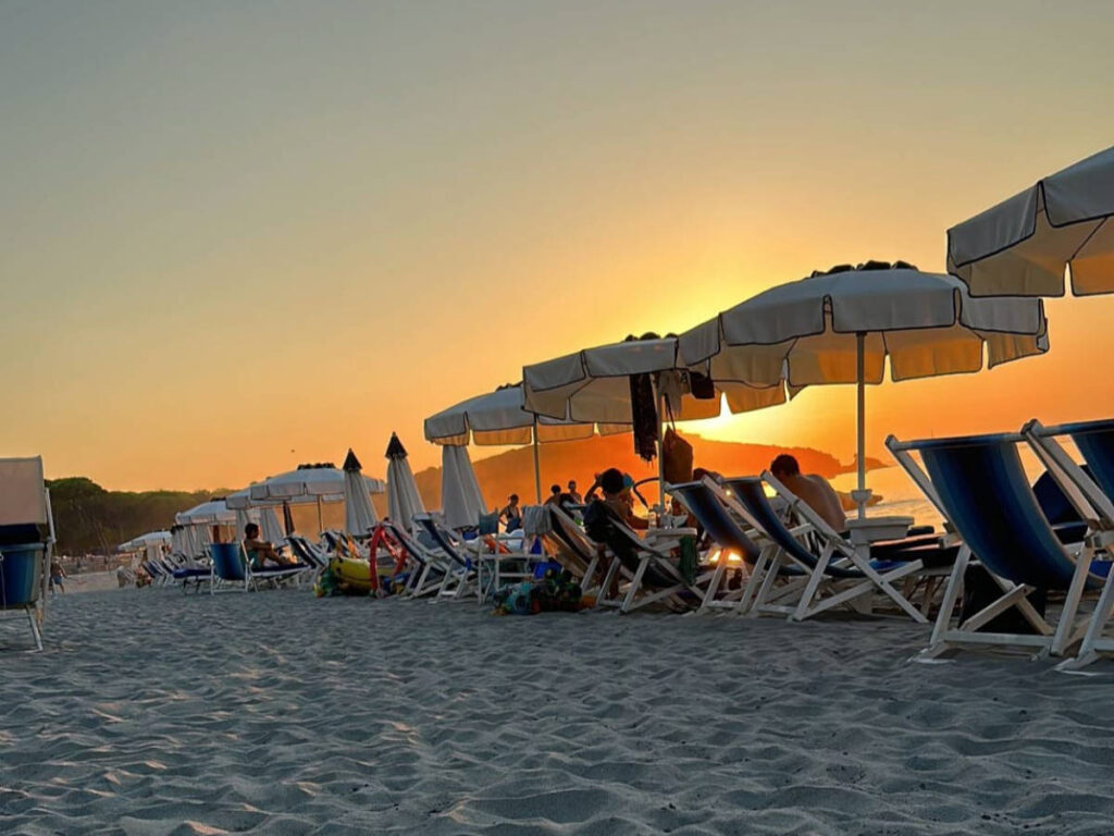 The lined lounge chairs facing the Golfo di Baratti Beach seen at sunset