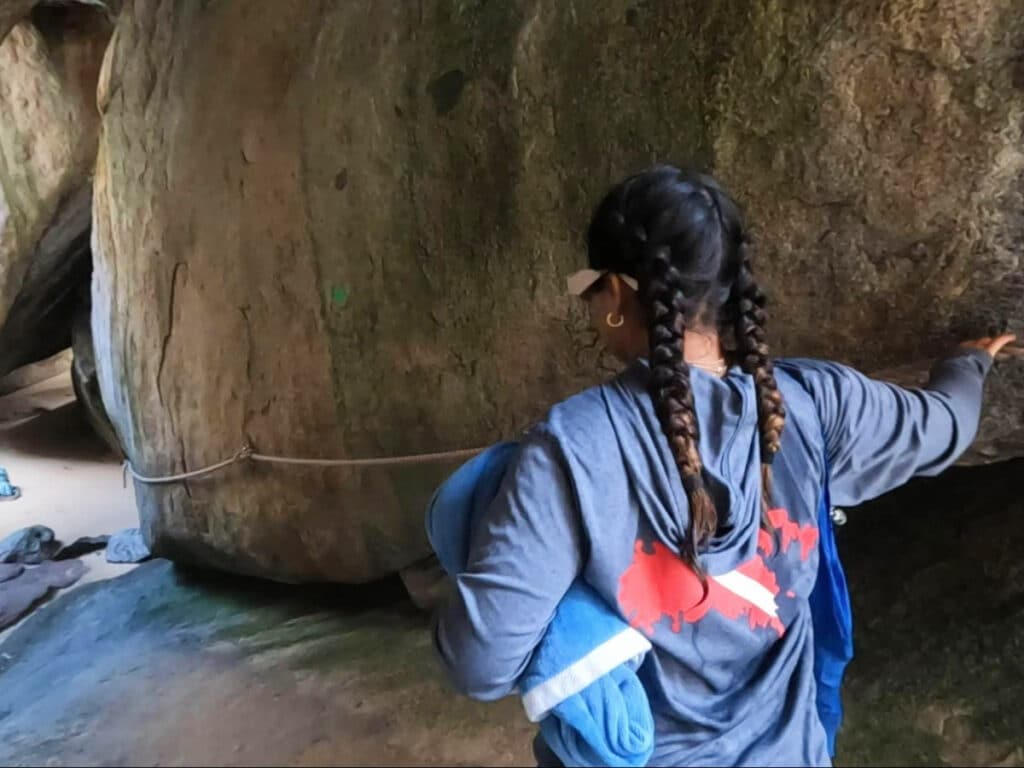 A girl entering a tunnel mad by granite boulders