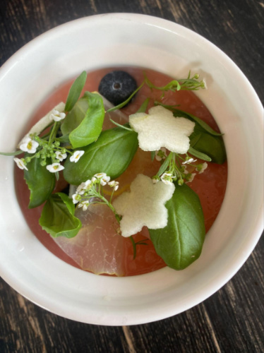 A bowl of guava pana cotta topped with guava leaves, flowers and flower shaped guava