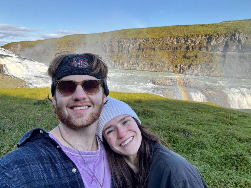 The author, Betty Hurd with her partner smiling for a selfie with the Gullfoss Waterfall on their background