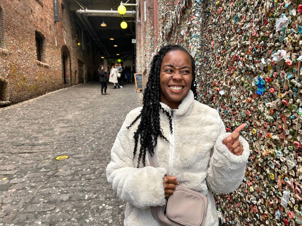 The author, Chelsea Booker pointing at the Gum Wall in Pike Place Market