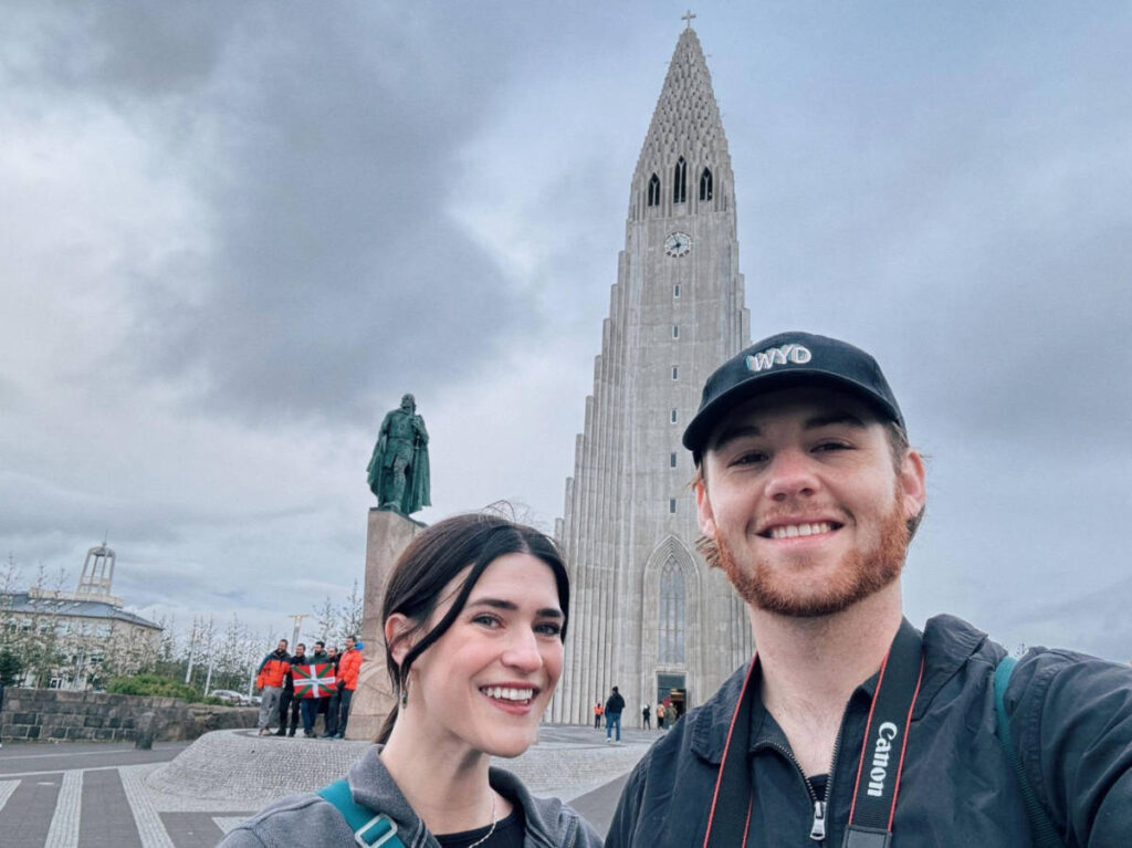 The author, Betty Hurd with her boyfriend smiling for a photo with the Hallgrímskirkja church on their background