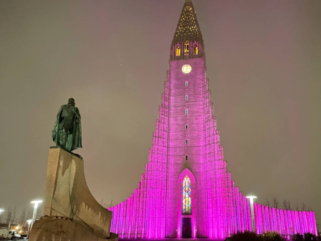 The illuminated Hallgrímskirkja and a statue at night
