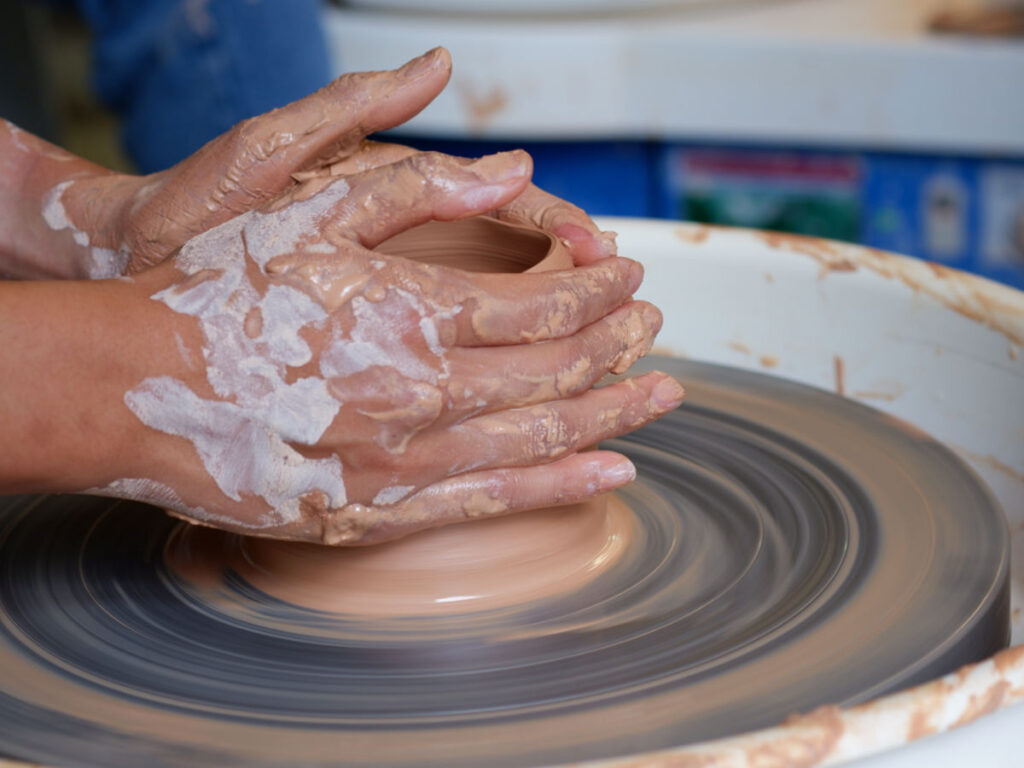 A person making a clay pottery on the throwing wheel