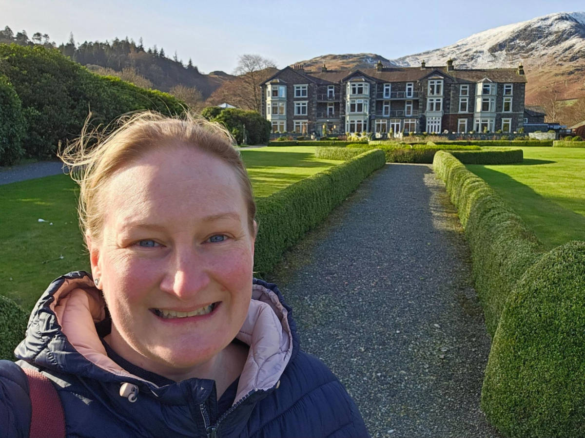 The author Heather Cole, smiling for a photo in front of the Inn on the Lake