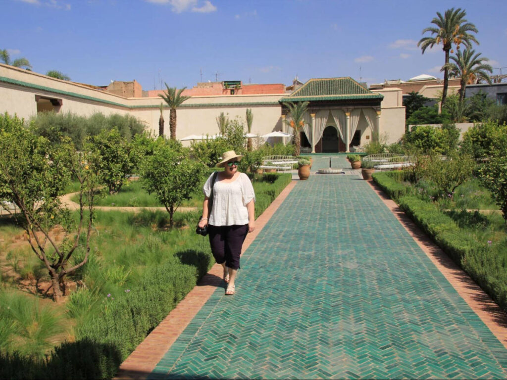 The author Heather Cole, walking along a green pathway at Le Jardin Secret surrounded by greenery