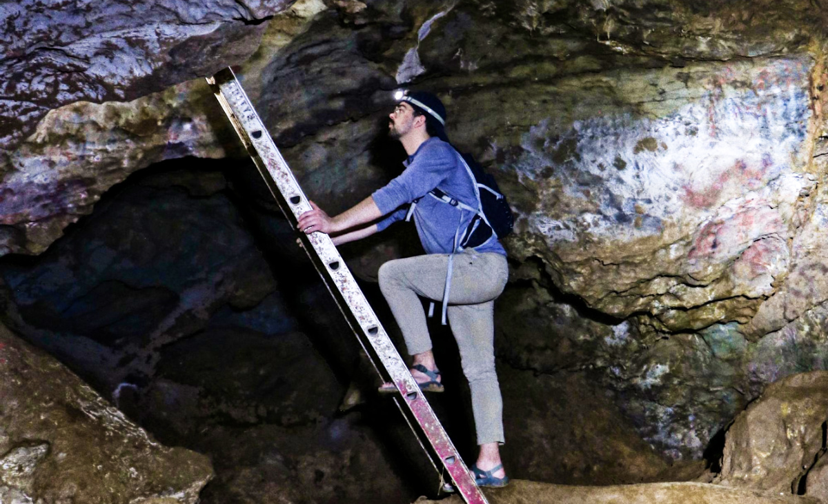 A man climbing a ladder inside the cavern