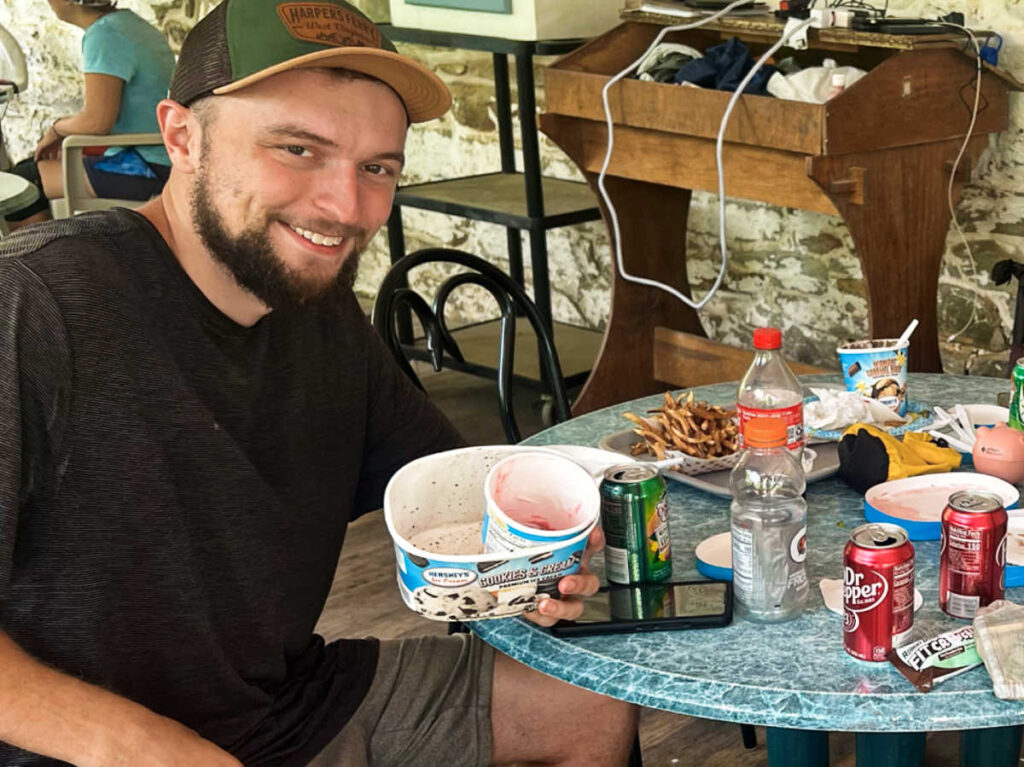 A hiker completing the half-gallon challenge with snacks and drinks on the table
