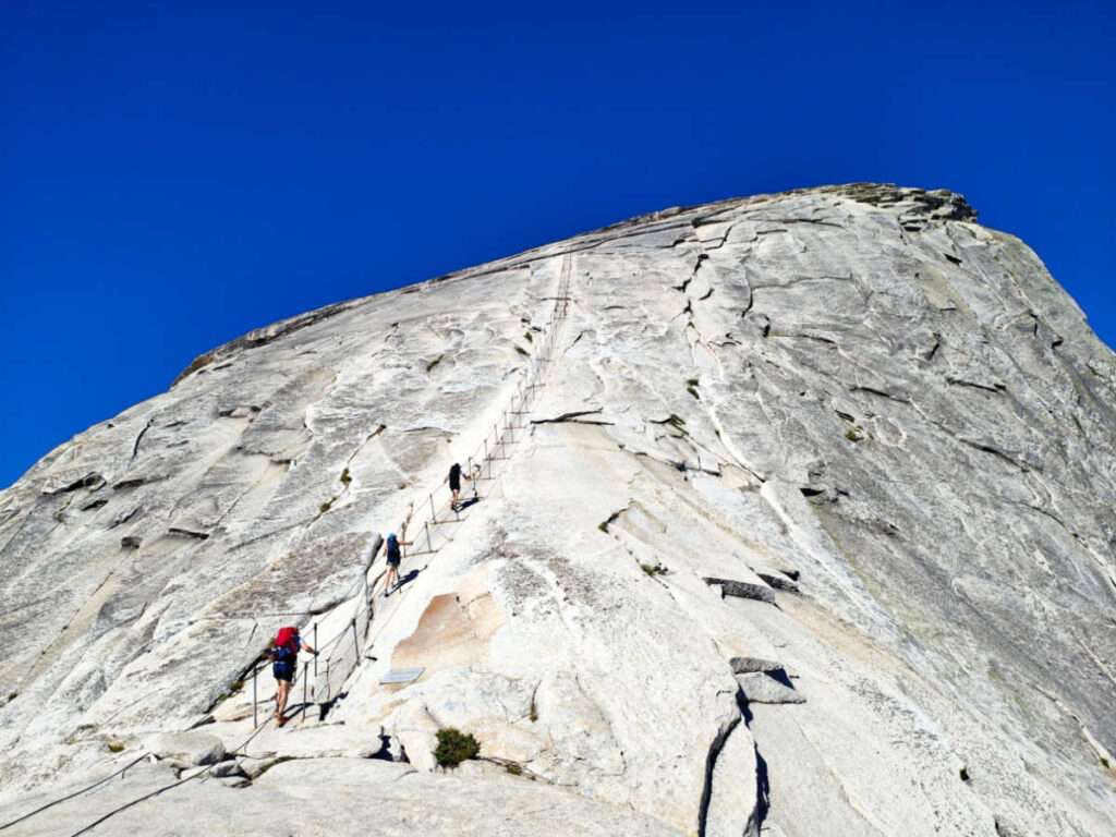 View of the hikers, hiking to the steep cable trail to the summit of the Half Dome