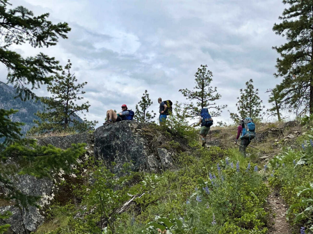 The backpackers resting on top of a rock on the trail