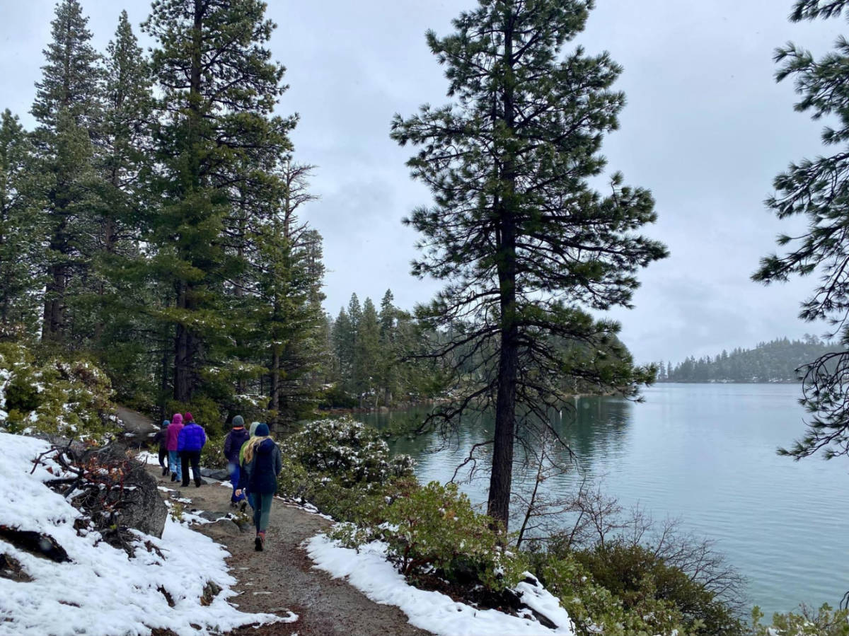 View of a group of hikers on the Rubicon Trail with an overlooking view of the lake