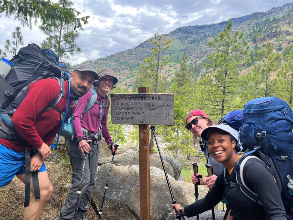 Author Chelsea Booker and her family posing at the Lakeshore Trail signage on their journey to Stehekin