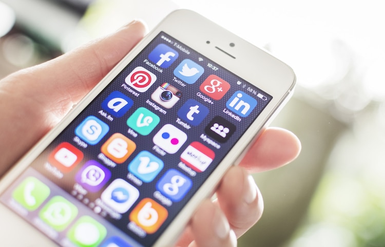 Person holding a smartphone with social media icons on screen