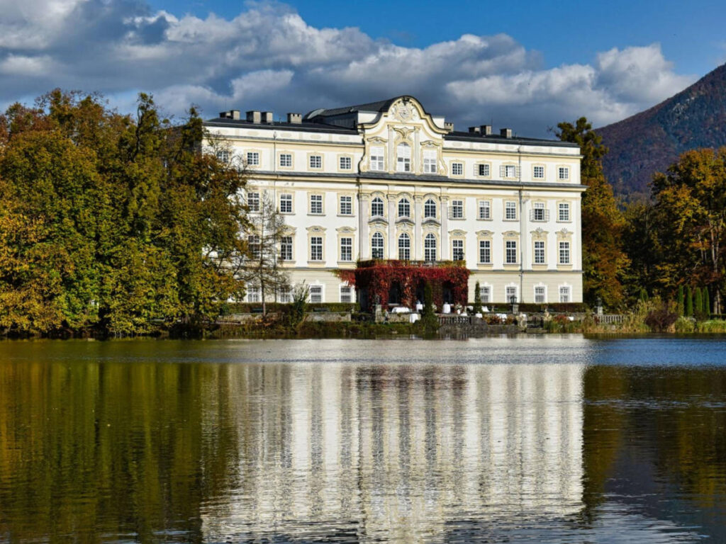 The exterior view of Hotel Schloss Leopoldskron reflecting in the water