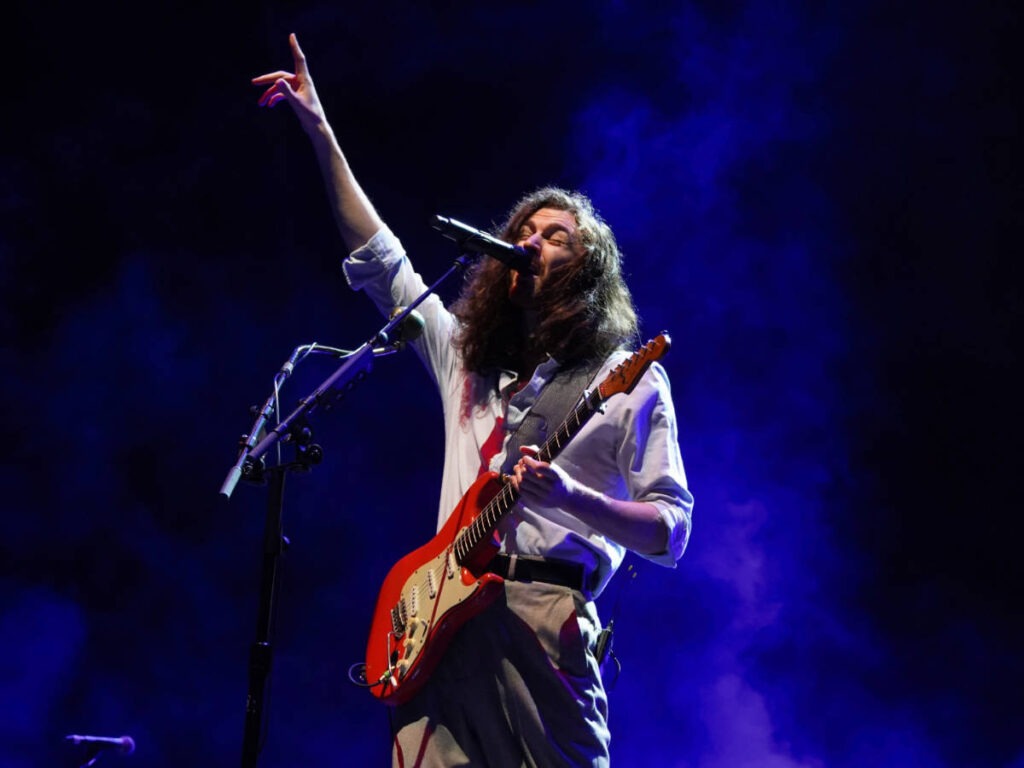Hozier holding his guitar while performing