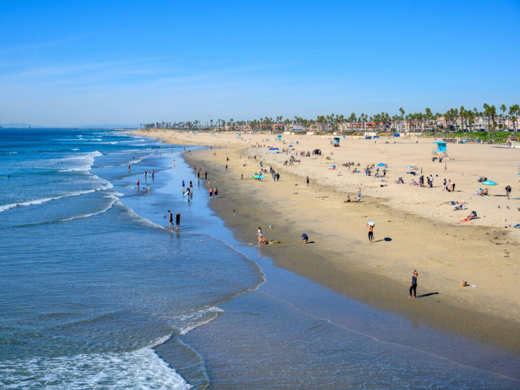 Aerial view of the crowd enjoying along the long stretch shoreline of Huntington Beach