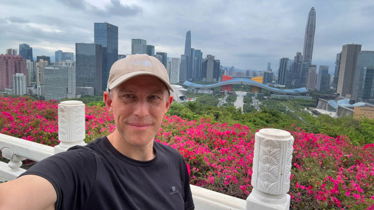 The author Ian Trower, smiling for a photo with skyline views in Lianhuashan Park